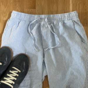 Randiga shorts från Daniel De Prato - Snygga blå- och vitrandiga shorts från Daniel De Prato  i luftig linneblandning. De har elastisk midja med snörning och avslappnad passform, perfekta för varma dagar. Klassisk sommarstil med fickor i sidorna och skön känsla mot huden.