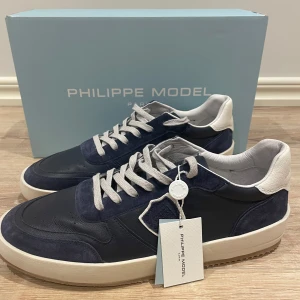 Philippe Model Blå Nice Tennis Navy - Snygga sneakers från Philippe Model i mörkblått skinn och mocka. Helt nya och aldrig använda. Storlek 45 och skickas med alla tillbehör. 
