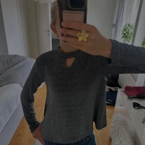 Glittrig svart långärmad blus - Snygg svart långärmad topp med glittrigt tyg och en liten cut-out vid halsen. Materialet är mjukt och stretchigt, vilket gör den bekväm att bära hela kvällen. Passar perfekt vid festligheter som nyår!🎊