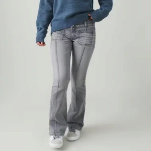  flare jeans - Flare jeans från Gina Tricot Young med sydda pressveck framtill. Jeansen är gråa och har låg stretch. De har utsvängda ben, låg midja och fickor fram och bak.