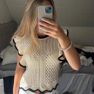 Stickad tröja med volang från Zara - Supersöt stickad ströjs från Zara i offwhite med svarta kanter. Tröjan har volangdetaljer längs ärmhål och nederkant samt ett unikt virkat mönster framtill och baktil. Klicka gärna på ”köp nu”!