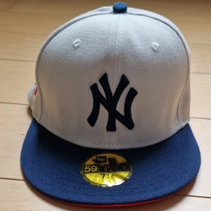 New Era Yankees 59FIFTY World Series keps (Limited edition) - Väldigt sällsynt och snygg New Era 59FIFTY keps med New York Yankees-logga framtill, broderad World Series 1996 patch på sidan och MLB-logga bak. Kepsen är vit med blå skärm och röd undersida. Klassisk basebollstil, perfekt för dig som gillar sport och streetwear eller bara att ha snygga kepsar. Storlek 61.5 cm runt huvudet. Säljs då den är för liten för mig.