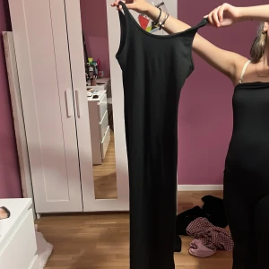 Svart långklänning från Shein - Säljer en svart långklänning från Shein med smala axelband och rak, figurnära passform. Klänningen är ärmlös och har en enkel, stilren design som är lätt att matcha med accessoarer. Perfekt för dig som gillar minimalistisk stil.