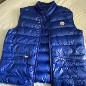 Moncler väst blå - Det är en blå Moncler väst jag fick av min brorsa för ish 3 år sedan tror jag den är super fin och inga skavanker jag har använt den max tre gånger då den är för liten för mig, den är köpt på NK i Stockholm, NK påse följer med men jag har inte varken kvitto eller prislapp kvar. Pris går att diskutera!