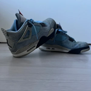 Nike Air Jordan 4 University Blue - Nike Air Jordan 4 University Blue med ljusblå mocka, meshpaneler och svarta detaljer. Snygga speckled grå inslag på sidorna och klassisk Jumpman-logga under sulan. Skorna har snörning och en chunky sula med synlig Air-enhet. Pris går att diskuteras storleken är liten mellan 39-40