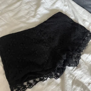 Svarta spets-shorts från Lindex - Svarta shorts från Lindex med blommig spets och fina detaljer längs kanten. Storlek 38 men passar som 36 också