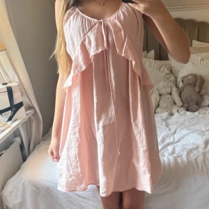 Ljusrosa klänning med volang - Jätte gullig ljusrosa klänning med fina volanger, använd en gång innan men har tyvärr inte kommit till användning. Otroligt bra skick, skönt på sommaren då den är luftig men kan användas både till vardags eller festliga sammanhang! Skulle säga att klänningen är i storlek xs-s, från H&M