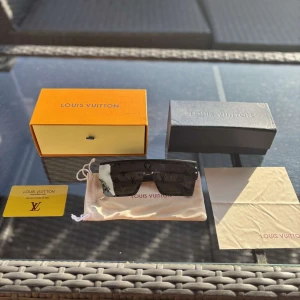 Svarta Louis Vuitton solglasögon - Snygga svarta solglasögon från Louis Vuitton med breda skalmar och rektangulär form. Glasen har LV-monogram över hela ytan för en lyxig vibe. Kommer med originalbox, fodral och putsduk. Perfekta för dig som vill sticka ut med exklusiv stil. Ordinarie pris 5000kr