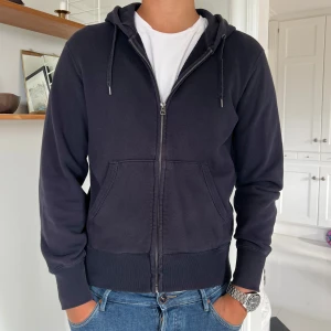 Svart hoodie med dragkedja - Svart hoodie med hel dragkedja och huva ifrån Uni Qlo. Tröjan har tyvärr blivit lite solblekt och därav de låga priset 