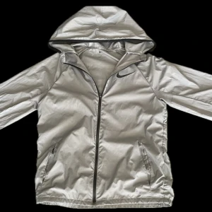 Nike windbreaker  - Säljer en fet windbreaker från Nike! Jackan är i storlek 158 men skulle säga att den passar större, den har ett litet hål vid vänstra fickan (se på sista bilden). Annars är den i bra skicka, hör av er om ni har några funderingar 
