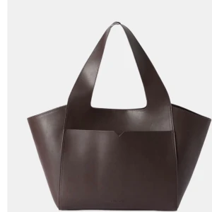 Carin Wester väska  - Stor totebag i imitationsläder som rymmer alla nödvändigheter. Väskan har breda axelremmar som sömlöst löper upp från den rymliga väskan. Väskan har en stor öppen ytterficka med V-design, och ett hängande innerfack med kortficka inuti. Väskan är som ny! Nypris 599! 