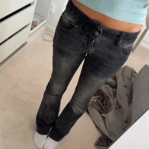Svarta bootcut jeans med tvättad look - Säljer ett par svarta jeans med bootcut-modell och snyggt tvättad finish. Använda men i bra skick! Min spegel som är smutsig inte jeansen! Dom har små slitningar längst ner på kanten men inget man tänker på!