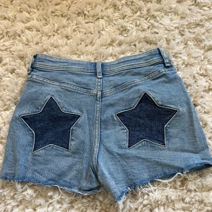 Jeansshorts med stjärnor - Snygga ljusblå jeansshorts från H&M med stjärnor på baksidan. Storlek 164 men skulle säga XS/S. Stretchiga, använda fåtal gånger och är i bra skick!