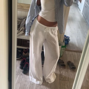 Vita linnebyxor med snörning - Säljer ett par fräscha vita linnebyxor med breda ben ifrån Nelly. Dom är väldigt långa, jag är 167 och bilden visar hur långa dom är på mig men går nog lätt att sy upp. Prislappen är kvar, aldrig använda.
