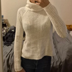 Vit polotröja från Gina Tricot - Säljer en vit polotröja från Gina Tricot i storlek XS. Tröjan är stickad med ribbad struktur, har lång ärm och hög polokrage som är perfekt för kyliga dagar. Modellen är lite loose med slits på sidorna för extra comfy vibe. Passar dig som gillar enkel och stilren look.