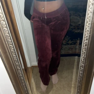 Vinröda sammetsbyxor med fickor - Säljer ett par vinröda sammetsbyxor med normal passform och resår i midjan. Byxorna har fickor fram och bak, samt snygga detaljer med knappar på bakfickorna. Perfekta för dig som vill ha en mjuk och chill look.