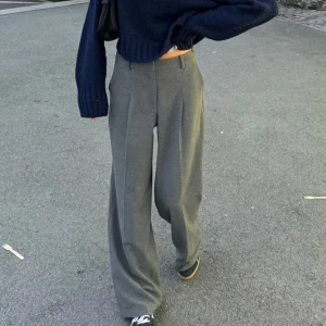 Gråa vida kostymbyxor - Snygga grå kostymbyxor med hög midja och vida ben. Byxorna har pressveck framtill och klassiska hällor för bälte. Säljes pga att de var lite för stora på mig🩶🩶