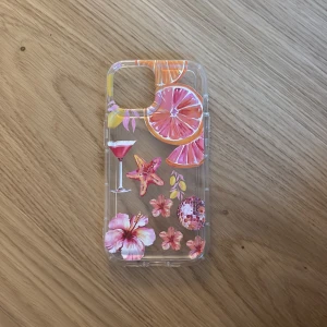 Somrig mobilväska iPhone 15 - Säljer ett genomskinligt mobilskal med färgglada motiv av grapefrukt, blommor, drink och discokula. Perfekt för dig som vill ha en tropisk vibe på mobilen! Skalet har rosa, orange och gula detaljer och är gjort i tålig plast. Aldrig använt!! Pris kan diskuteras!