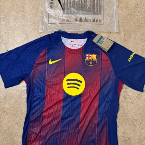 FC Barcelona Gavi matchtröja Nike - FC Barcelona matchtröja med Gavi och nummer 6 på ryggen. Klassiska blå och röda ränder, gula detaljer och klubbmärke på bröstet. Nike-logga och Spotify som sponsor framtill. Tillverkad i lätt, ventilerande funktionsmaterial.