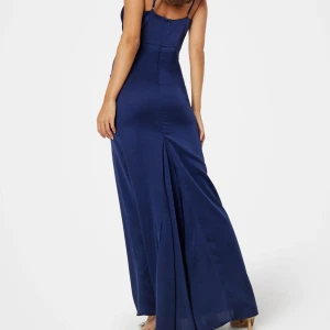 Marinblå långklänning med smala axelband - Säljer en elegant marinblå långklänning med smala axelband och figurnära passform. Klänningen är tillverkad i ett glansigt, mjukt material som ger en lyxig känsla. Perfekt för bal eller festliga tillfällen.