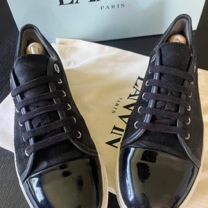 Svarta Lanvin captoe - Snygga svarta sneakers från Lanvin med ovandel i mocka och exklusiv lackad tå. Skorna har svarta snören. Har box och dustbag öppen för byten och prisförslag. Dem är storlek 42 men passar större. Sulan har blivit heeldragad men har lagat