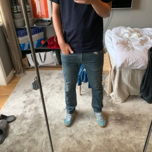Levi's 504 straight blå jeans - Säljer ett par klassiska Levi's 504 straight jeans i blå denim. De har normal passform, raka ben och snygga slitningar för en avslappnad look. Jeansen har fem fickor, gylf med dragkedja och är tillverkade i bomull. Perfekta för dig som gillar tidlös stil.