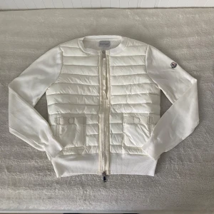 Vit Moncler Cardigan för tjejer - En helt ny vit Moncler Cardigan i storlek 2 (motsvarar S) Jag köpte den åt min flickvän men den passade inte henne tyvärr så jag återstäljer den - skriv om eventuella frågor!