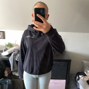 Mörkblå hoodie från Gina Tricot med tryck - Mörkblå hoodie från Gina Tricot med vit text och två hjärtan tryckta på ryggen. Tröjan har huva, snörning och långa ärmar. Perfekt för dig som gillar en chill och snygg streetstil.