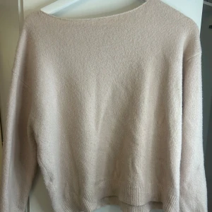 Baby rosa stickad tröja från MANGO - Supermjuk och enkel baby rosa stickad tröja från MANGO. Tröjan har en avslappnad passform, hänger asymmetriskt av ena axeln. 