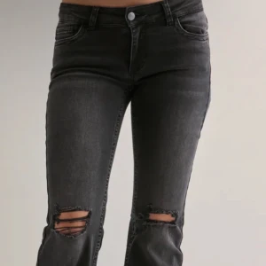 Svarta utsvängda jeans med hål på knäna  - Snygga svarta utsvängda jeans med slitningar över knäna och cool broderad detalj på bakfickorna