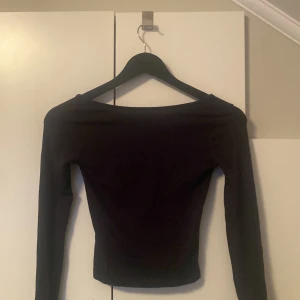 Svart långärmad topp Gina Tricot - En svart långärmad topp från Gina Tricot med bred, något båtformad urringning. Modellen är figurnära och enkel, perfekt att styla med jeans eller kjol. Mjuk och stretchig känsla i materialet för en bekväm passform.💞