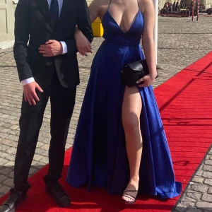 Marinblå långklänning med slits - Säljer en marinblå långklänning med djup v-ringning, smala axelband och öppen rygg med snörning. Perfekt för bal eller liknande. Jag är 173 cm lång, klänningen är inköpt på dressroom linné i Göteborg och är använd med omtanke 🩵