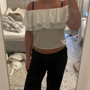 Vit offshoulder volangtopp - Supersöt vit offshoulder topp med dubbla volanger runt hela överdelen. Croppad modell som sitter snyggt över axlarna och ger en fräsch sommarkänsla. 