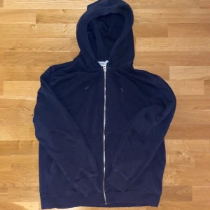 Mörkblå hoodie med dragkedja Weekday - Mörkblå hoodie från Weekday med hel dragkedja framtill och huva med snörning. Tröjan har långa ärmar, ribbade muddar och är tillverkad i mjuk bomull. Perfekt för chill dagar eller när du vill ha en enkel och stilren look.