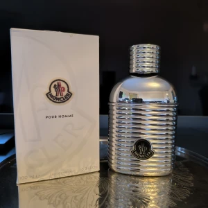 Moncler Pour Homme Eau de Parfum 100ml - Orginal batch - Moncler Pour Homme Eau de Parfum i en cool, ribbad silverfärgad metallflaska på 100 ml. Flaskan har en modern, maskulin design med Moncler-logga framtill och kommer med originalkartong. En exklusiv herrdoft som sticker ut både i doft och utseende. Knappt använd, som ny. Första batchen som tillverkades.