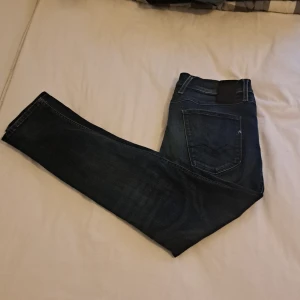 Blå jeans från Replay, straight fit - Snygga blå jeans från Replay med klassisk femficksdesign och raka ben. Jeansen har diskreta slitningar och detaljer som Replay-logga på bakfickan och metallmärke vid fickan. Perfekta för dig som gillar en tidlös och clean look. Köpta för 1200