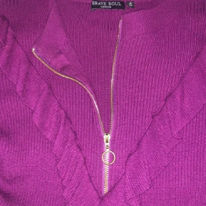 Lila stickad tröja med volang Brave Soul - Superfin lila stickad tröja från Brave Soul med volangdetaljer framtill och en snygg guldfärgad dragkedja med ring, köpte för 259kr, säljer pga för jag rensar min garderob men annars den är i jätte bra skick🤗💕