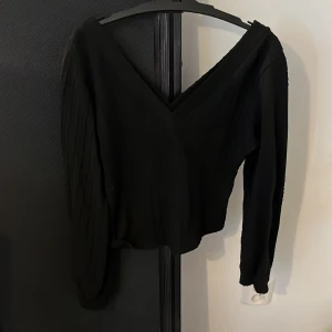 Svart stickad v-ringad tröja - Svart stickad tröja med v-ringning och lång ärm. Tröjan har ett diskret kabelstickat mönster och är lite loose i passformen. Perfekt för lager-på-lager och funkar året runt. Enkel att matcha med både jeans och kjol.