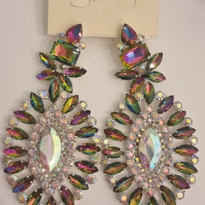 Glittriga statement örhängen i regnbågsfärger - Stora, glittriga statement örhängen med regnbågsfärgade stenar i olika former. Örhängena har en lyxig känsla med massor av gnistrande detaljer och reflekterar ljuset i flera färger. Perfekta för att sticka ut och ge din look extra wow-faktor.