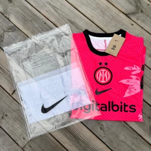 Inter Milan x Nike rosa fotbollströja - Snygg Inter Milan fotbollströja från Nike i stark rosa färg med svarta detaljer. Tröjan har korta ärmar, svart krage och coolt mönster med ormar och blad. Digitalbits-logga på bröstet och klubbmärke framtill. Tillverkad i lätt och ventilerande material. Pris kan diskuteras vid snabb affär 