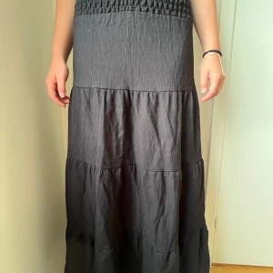 Svart långkjol med smock i midjan - Säljer en svart långkjol med låg midja och flera volanger. Säljer pga att den inte kommer till användning. Pris kan diskuteras!!❤️