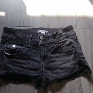 Svarta jeansshorts från Gina Tricot - Snygga svarta jeansshorts från Gina Tricot med råa kanter och slitna detaljer. Klassisk femficksmodell, dubbla knappar framtill och bälteshällor. Perfekta för sommardagar och enkel att matcha med allt. (Jag har klippt dom själv då dom tidigare var vanliga jeans)