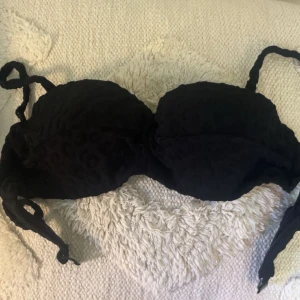 Svart bikiniöverdel med leopardmönster - Svart bikiniöverdel med subtilt leopardmönster och vadderade kupor. Knytband både i ryggen och axlarna för justerbar passform. Snygg och stilren modell som ger ett coolt intryck på stranden.