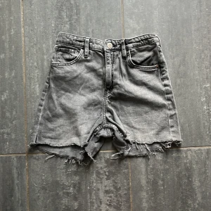 Gråa jeansshorts från H&M, high waist - Snygga gråa jeansshorts från H&M med hög midja och breda ben. Råa, fransiga kanter ger en cool och avslappnad vibe. Klassisk femficksmodell i denim, perfekta för sommardagar. 