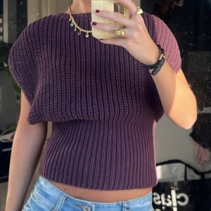 Mörklila stickad topp från Zara - Säljer en mörklila stickad topp från Zara med bred ribbstickning och indragen midja. Modellen är ärmlös med rund halsringning och har en loose fit upptill som smalnar av vid midjan. 