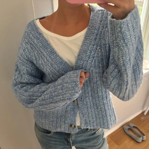 Ljusblå stickad kofta med knappar - Supermysig ljusblå stickad kofta med grov ribbstickning och stora knappar framtill. Koftan har en avslappnad passform, v-ringad hals och långa ärmar. Använd få gånger, strl s