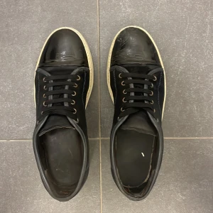 Svarta Lanvin sneakers i mocka  - Stilrena marinblå sneakers från Lanvin med vita sulor och glansig toebox.skick 7.5 av 10 
