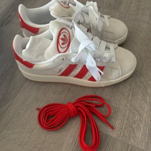 Campus 00s "Crystal White Better Scarlet"  - Säljer dessa Adidas Campus 00s "Crystal White Better Scarlet". Vita skosnören och extra röda skosnören medföljer. Storlek 38 2/3. Aldrig använda, bara testade & lappen sitter kvar💗(köpta för 1999kr)