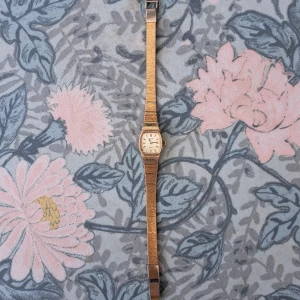 Guldig vintageklocka från Pulsar - Snygg och stilren vintageklocka från Pulsar i guldtonad metall med fyrkantig urtavla och diskreta index. Armbandet är smalt och elegant, och baksidan är i rostfritt stål. Perfekt accessoar för dig som gillar retrostil och klassisk design.