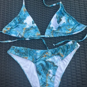 Blåvit bikini med marmorprint - Snygg bikini med blått, vitt och orange marmorprint. Överdelen är trekantsmodell med knyt i nacke och rygg, och underdelen har klassisk passform. Perfekt för stranden och poolen, riktigt fräsch och trendig look. Från shein men köpt i fel storlek.